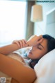 A woman laying in bed with her hand on her head.