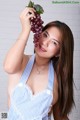 A woman in a blue and white dress holding a bunch of grapes.