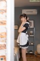 A woman in a maid outfit standing in a room.