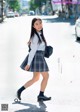 A young woman in a school uniform is walking down the street.