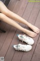 A woman sitting on a wooden deck with her feet up.