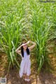 A woman in a white dress standing in a field of sugarcane.