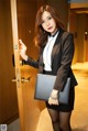 A woman in a black suit holding a black purse.