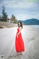 A woman in a red dress standing on a beach.