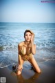 A woman in a bikini sitting on the beach.