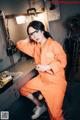 A woman in an orange jumpsuit sitting at a table.