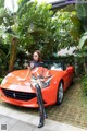 A woman sitting on top of a red sports car.