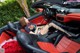 A woman sitting in the driver's seat of a red and black car.