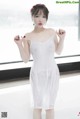 a woman in a white dress standing in front of a window