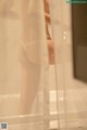 A woman in a white thong standing in a shower.