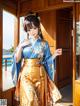 A woman in a blue and gold kimono standing in front of a window.