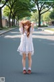 A woman in a white dress is standing on the street.