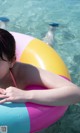 A woman in a pink bikini laying on an inflatable ring in a pool.