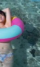 A woman in a bikini laying on an inflatable ring in the water.