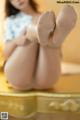 A woman sitting on top of a dresser with her feet up.