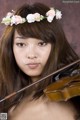 A woman with a flower crown on her head holding a violin.