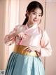 A woman in a pink and blue hanbok is posing for a picture.