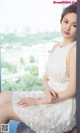 A woman in a white dress sitting on a window sill.