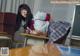 A woman in a school uniform is sitting at a desk.