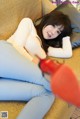 A woman laying on a couch with a pair of red shoes.