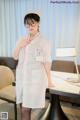 A woman dressed as a nurse standing in front of a table.