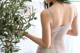 A woman in a white lingerie standing next to a plant.