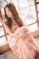 A woman in a pink dress sitting on the steps of a building.