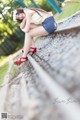 A woman sitting on a train track with her legs crossed.