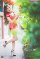 A woman in a red and yellow cheongsam posing for a picture.