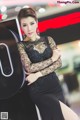 A woman in a black dress posing next to a washing machine.