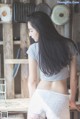 A woman in a gray shirt and white panties standing in a kitchen.