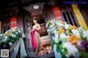 A woman standing in front of a building with flowers.