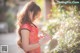 A woman in a red dress holding a flower.