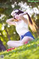 A woman sitting on the grass with a flower crown on her head.