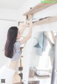 A woman standing in front of a mirror holding a shelf.