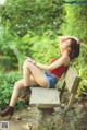 A woman sitting on a wooden bench in a park.