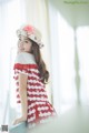 A woman in a red and white dress and a straw hat.