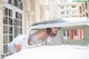 A woman in a white dress leaning out the window of a car.