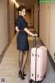 A woman in a blue dress with a pink suitcase.