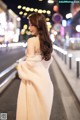 A woman in a white dress is walking down the street.