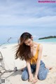 A woman sitting on a sandy beach next to the ocean.