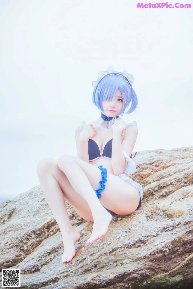 A woman in a bikini sitting on a rock.
