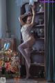 A woman in a white lingerie posing in front of a bookcase.