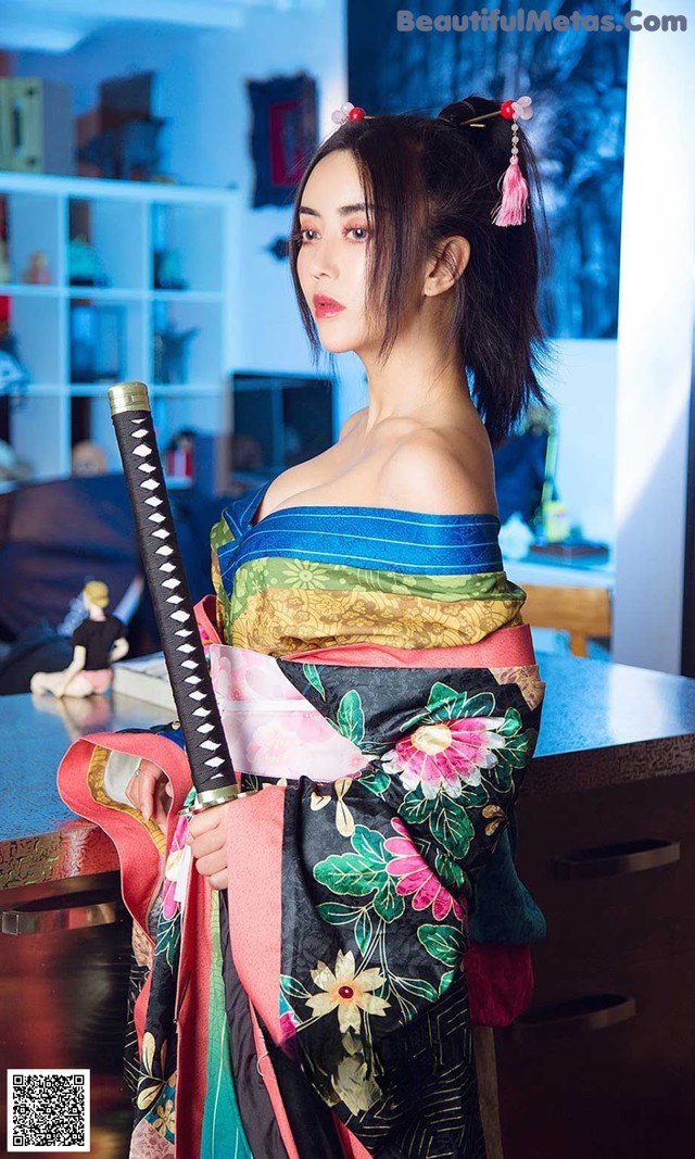 A woman in a kimono holding a samurai sword.