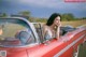 A woman sitting in the driver's seat of a red convertible car.