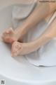 A woman's feet in a bathtub with clear stockings.