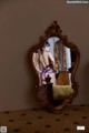 A woman standing in front of a mirror in a bedroom.