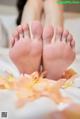 A close up of a person's feet with rose petals on the bed.