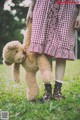 A little girl holding a teddy bear in the grass.