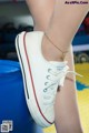 A close up of a person wearing a pair of white shoes.